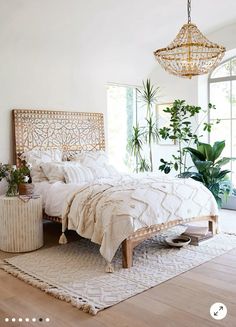 a bedroom with a bed, rug and plants in the corner on the floor next to it