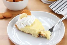 a piece of pie on a plate with a fork and bowl of cookies in the background