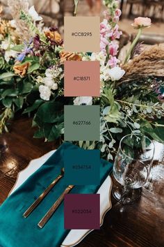 the table is set with flowers and place settings in shades of brown, pink, blue, green