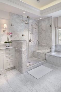 a white bathroom with marble flooring and walls, along with a walk in shower