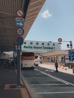 there is a bus that is stopped at the airport and people are walking on the sidewalk