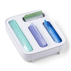 three different colored toothbrushes in a white box