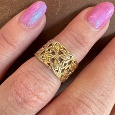 a woman's hand with a pink manicure and gold ring on her finger