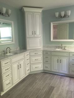 a large bathroom with two sinks and mirrors on the wall, along with white cabinets