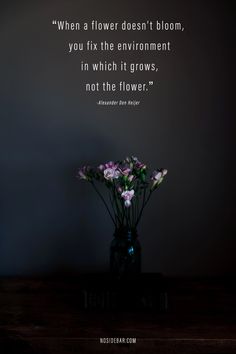 a vase filled with flowers sitting on top of a wooden table next to a wall