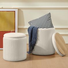 two white stools sitting on top of a hard wood floor next to a painting