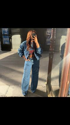 a woman standing in front of a mirror taking a selfie with her cell phone