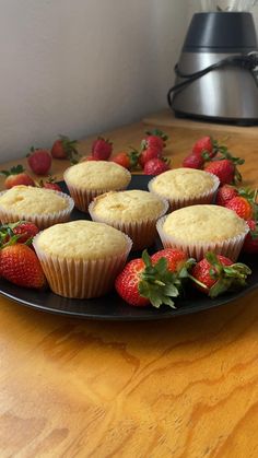 some strawberries and cupcakes on a black plate