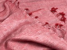 an old pink sweater with red thread on it and holes in the fabric that have been stitched together