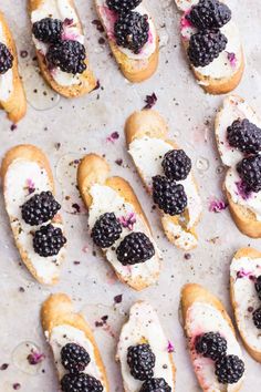 several bagels with blackberries and cream cheese on them are lined up in rows