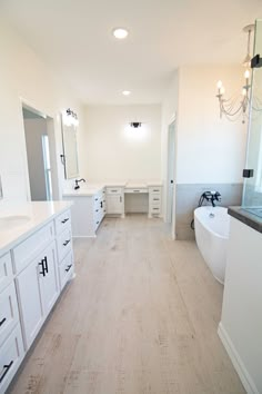 a large bathroom with white cabinets and wood floors