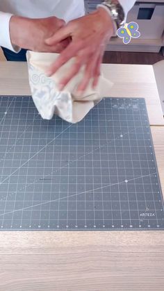 a person cutting fabric on top of a wooden table