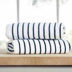 two black and white striped towels sitting on top of a wooden table next to a window