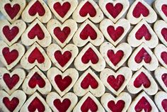 heart shaped cookies are arranged in rows on a table with red and white icing