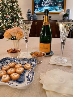 a table topped with wine glasses and plates filled with pastries next to a bottle of champagne