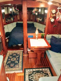 the inside of a sailboat with two beds and a table in the foreground