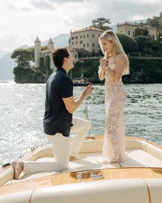 a man kneeling down next to a woman in a dress on top of a boat