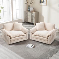 two beige chairs sitting on top of a gray rug