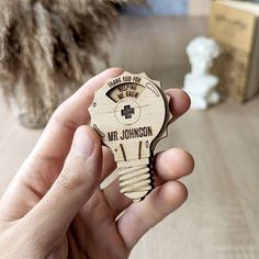 a person holding a wooden key shaped like a nurse's bottle opener with the words, thank you for nursing on it