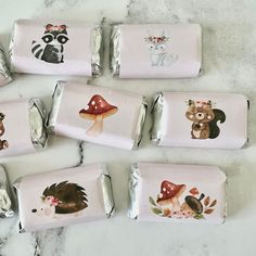 six wrapped candy bars with woodland animals and raccoons on them, sitting on a marble surface