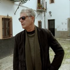 an older man wearing sunglasses standing in front of a building