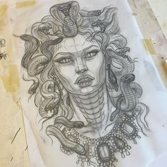 a drawing of a woman's face with snakes around her neck and head on paper