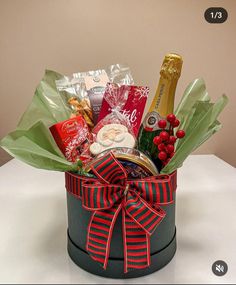 a christmas gift basket with champagne, cookies and candies in it on a table