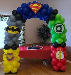 an arch made out of balloons with batman and green lantern symbols on it in the middle of a room