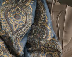 a blue and gold paisley pattern on a car seat cover that is folded up in the back