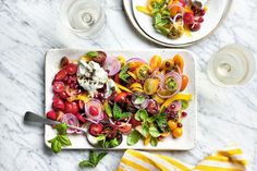 two plates with different types of vegetables on them and one plate with salad in it