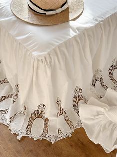 a hat is sitting on top of a white table cloth with lace trimmings