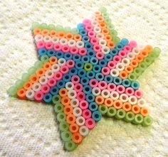 a star made out of plastic beads on a white surface with a crochet pattern