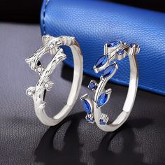 two silver rings with blue stones on top and one is in the shape of an arrow