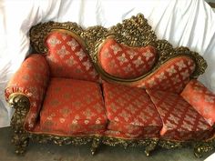 an ornate couch with red and gold upholstered fabric on it's back