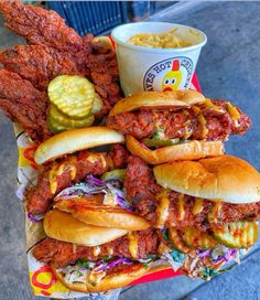 a tray filled with lots of different types of sandwiches and coleslaw on buns