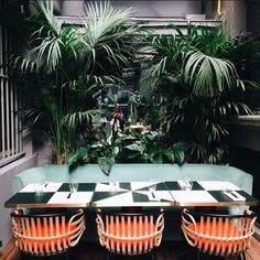 an outdoor dining area with green plants and checkered table cloths on the tables