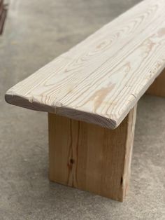 a wooden bench sitting on top of a cement floor