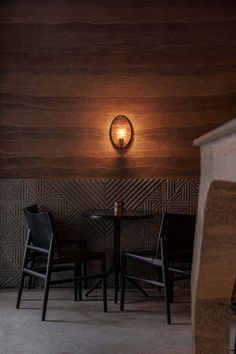 a table and chairs in a room with wood paneling on the wall behind it