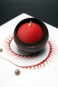 a small red object sitting in a bowl on top of a white surface with gold accents