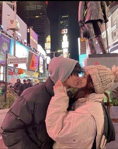 a man and woman standing next to each other in front of a statue at night