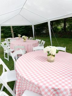 tables and chairs are set up under a tent for an outdoor party with pink gingham tablecloths