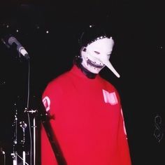 a person in a red shirt with a white mask on their face and a microphone