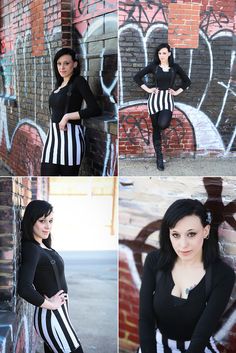 a woman in black and white striped dress posing for a photo with graffiti on the wall behind her