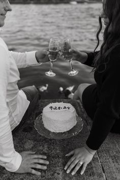 a man and woman toasting wine glasses over a cake