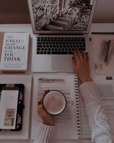 a person sitting at a desk with a laptop and coffee in front of them, surrounded by books