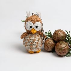 a crocheted owl keychain sitting next to some pine cones