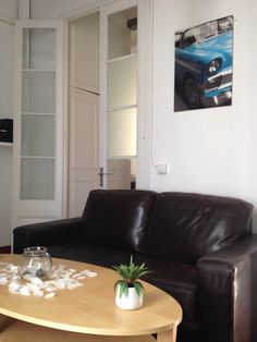 a living room with a brown leather couch and coffee table in front of a painting