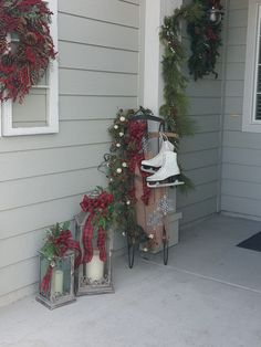 christmas decorations on the front porch of a house with wreaths and bells around it