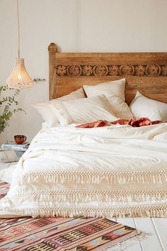 a bed with white sheets and pillows on top of it next to a lamp hanging from the ceiling