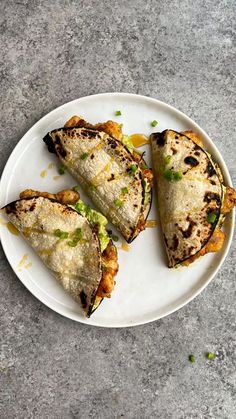 three quesadillas on a white plate with green garnish and seasoning